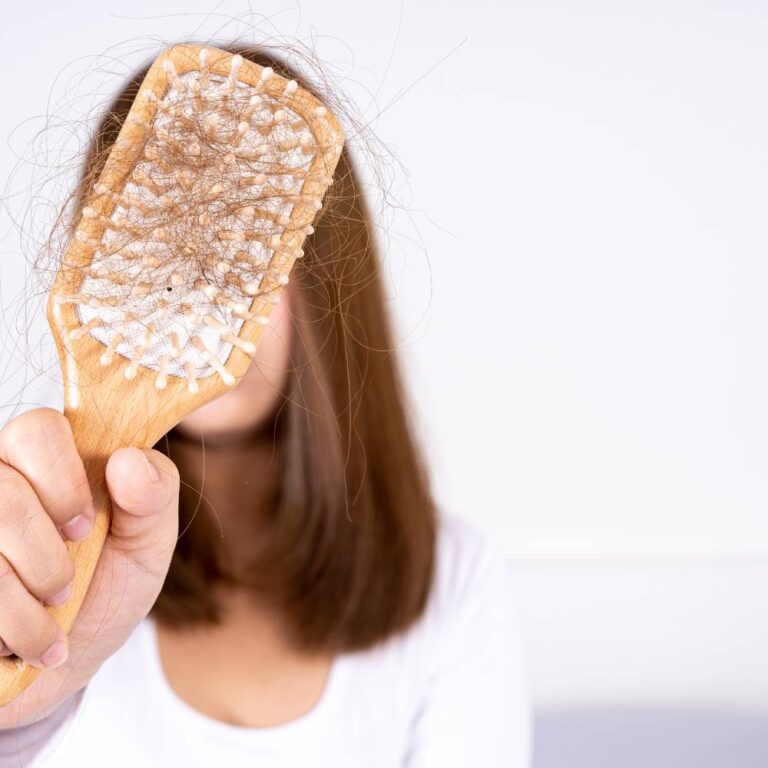 woman holding hair brush with lose hairs on it